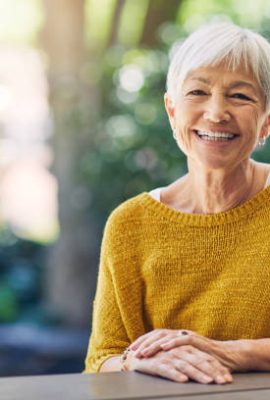 Shot of a happy senior woman sitting at a table in her backyard